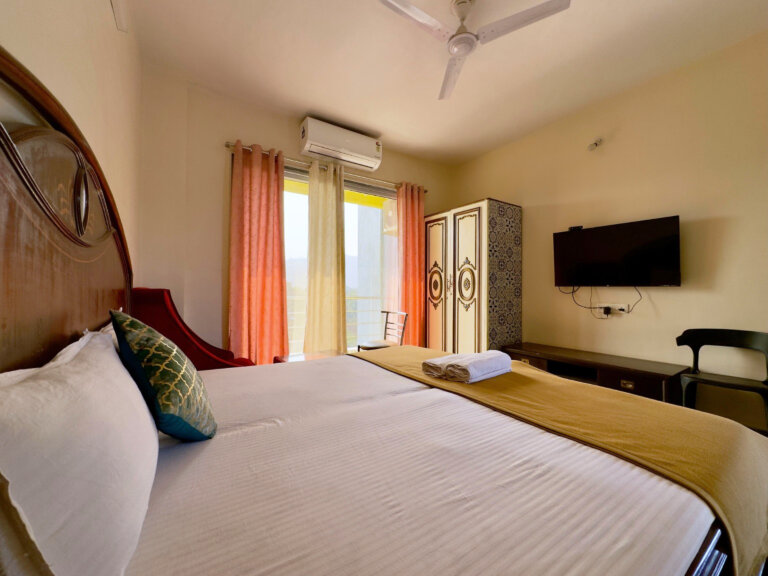 Bedroom with television and balcony doors at NB Nature Stay